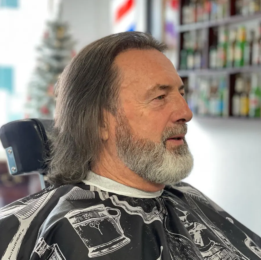 Cliente de cabelo comprido grisalho com a barba aparada e contornada