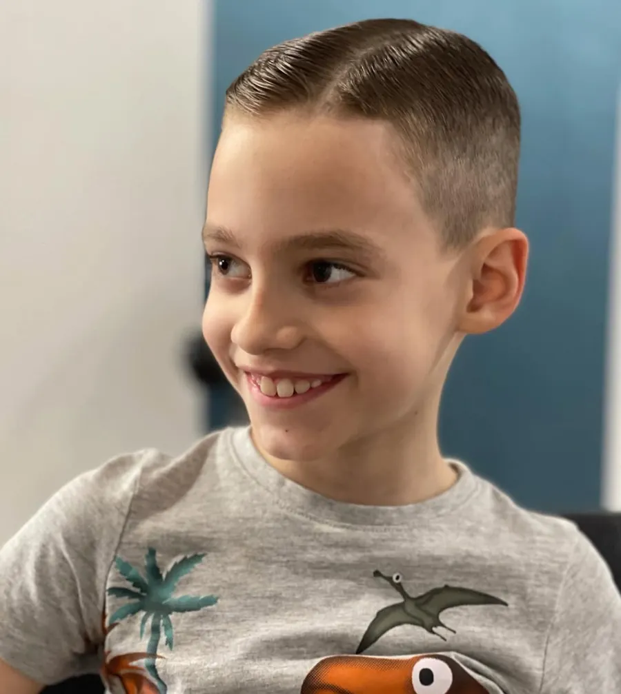 Criança sorridente com corte curto nas laterais e risca ao lado