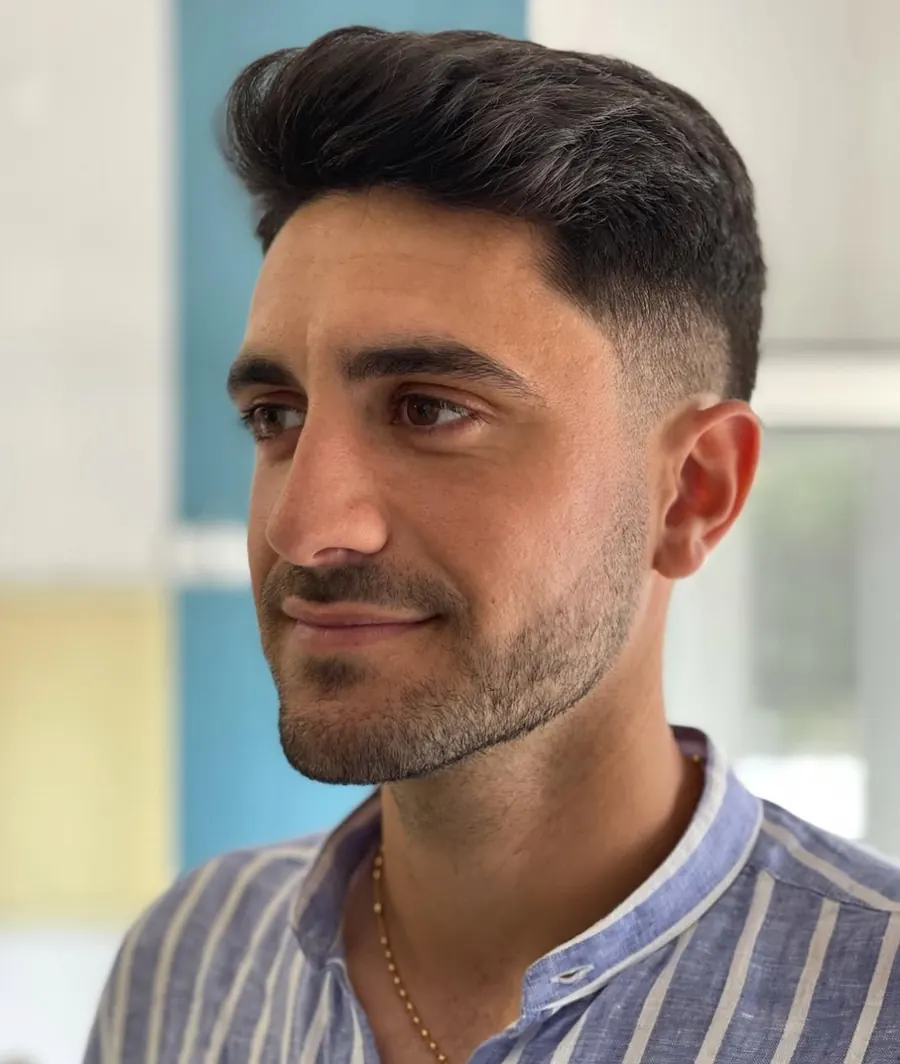 Corte com degradê baixo nas laterais e volume no topo, penteado para trás